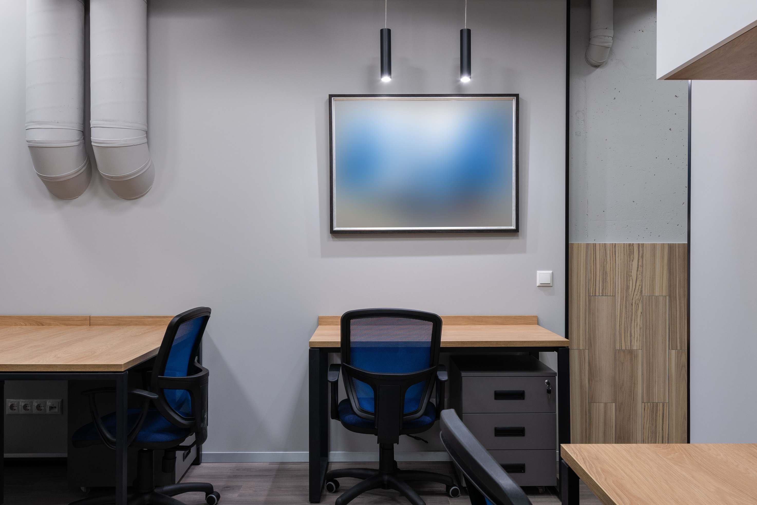 Helles, modernes Büro-Interior mit Tischen, Stühlen und grauen Wänden
